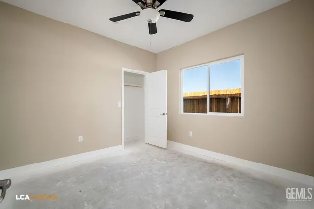 a view of an empty room with window and ceiling fan