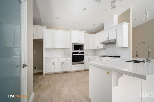 a kitchen with stainless steel appliances a refrigerator sink and white cabinets
