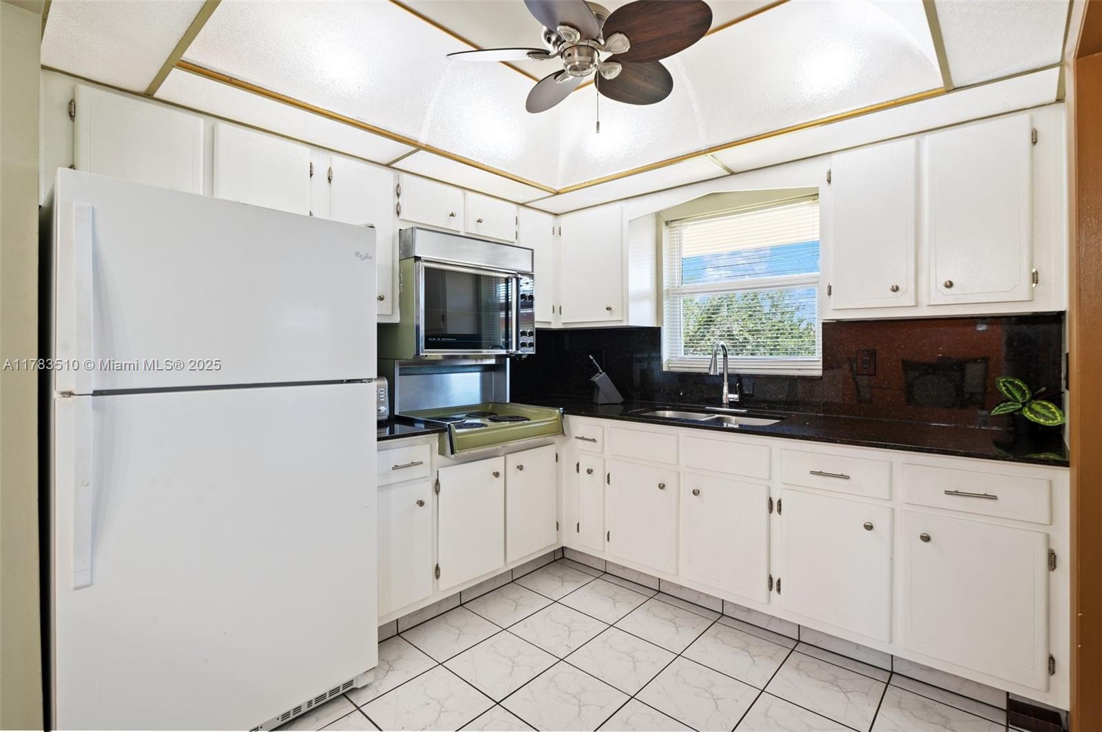5300 Washington Street, Unit G323 Hollywood, FL 33021 - Photo 13 of 34 a kitchen with granite countertop white cabinets and white appliances
