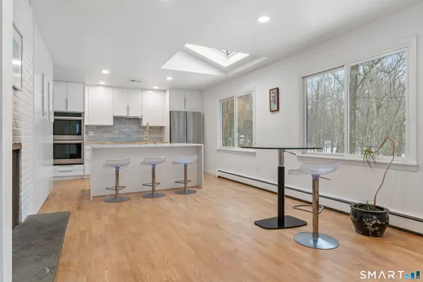 a living room with stainless steel appliances kitchen island granite countertop furniture and a wooden floor