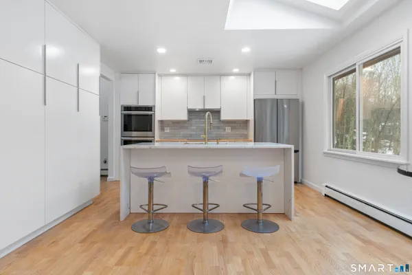a kitchen with kitchen island white cabinets and stainless steel appliances