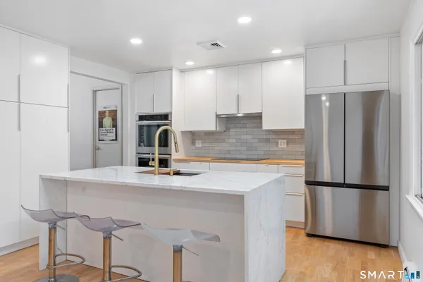 a kitchen with kitchen island white cabinets and stainless steel appliances