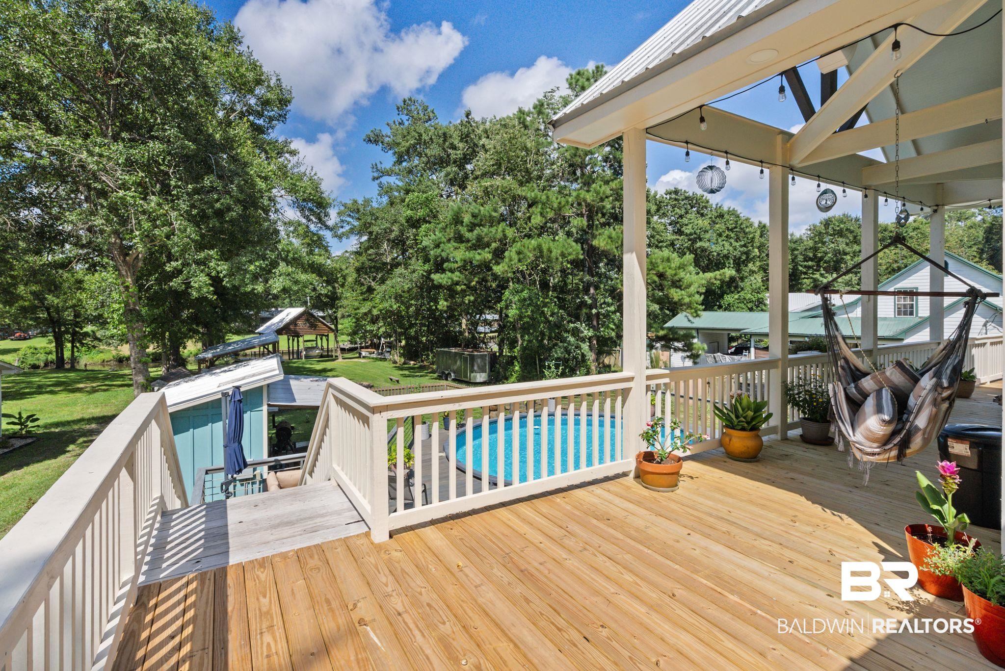7266 Franklin Road Foley, AL 36535 - Photo 50 of 64 Spacious outdoor decking with a white railing system, featuring a covered section with exposed beams and string lighting