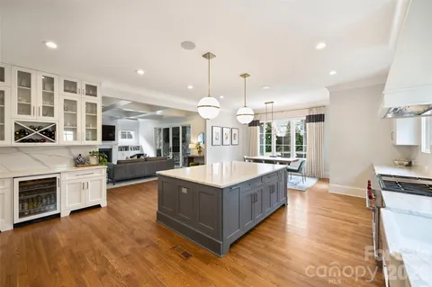 a large kitchen with stainless steel appliances kitchen island granite countertop a lot of cabinets and wooden floor