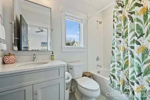 a bathroom with a granite countertop toilet a sink a mirror a shower curtain and a large mirror