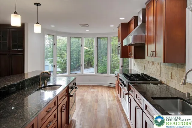 a large kitchen with stainless steel appliances a large counter top a stove and a wooden floors