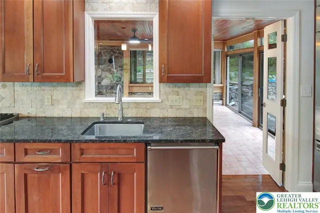 a view of an empty room with wooden floor fireplace and a window