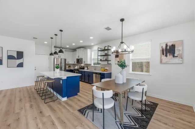 a kitchen with kitchen island a dining table chairs stainless steel appliances and cabinets