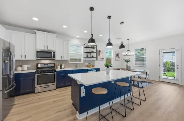 a large kitchen with kitchen island a stove a table and chairs in it