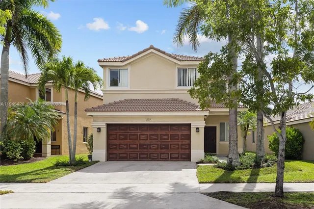 a front view of a house with a garden and palm trees