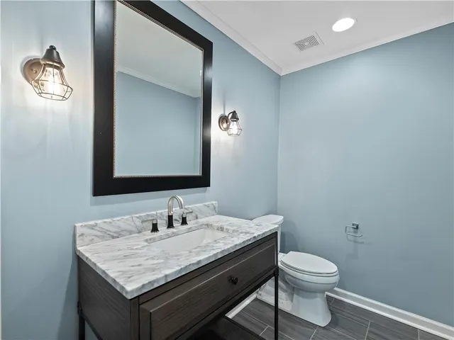 a bathroom with a granite countertop toilet a sink and a mirror