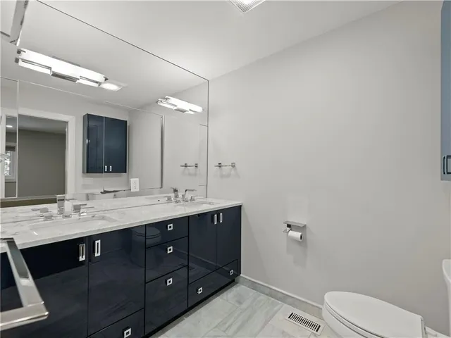 a bathroom with a double vanity sink toilet and a mirror