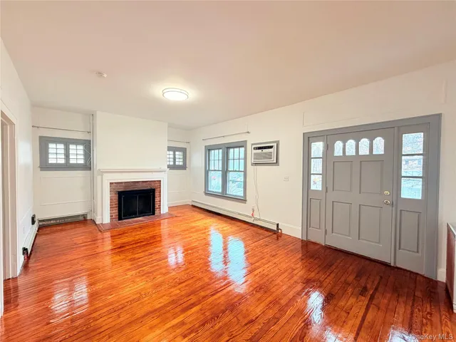 a view of empty room with wooden floor and fireplace