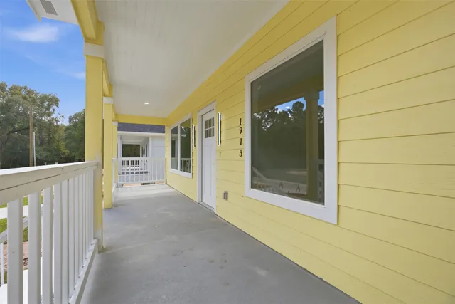 a view of a hallway with wooden floor and a bathroom