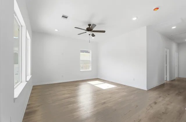 an empty room with windows and fan
