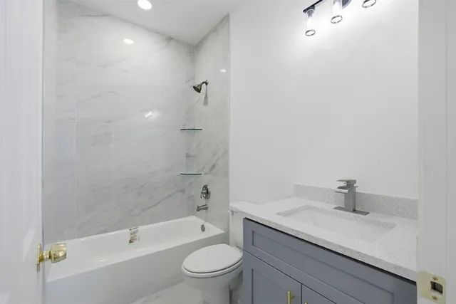 a bathroom with a granite countertop sink a toilet and shower