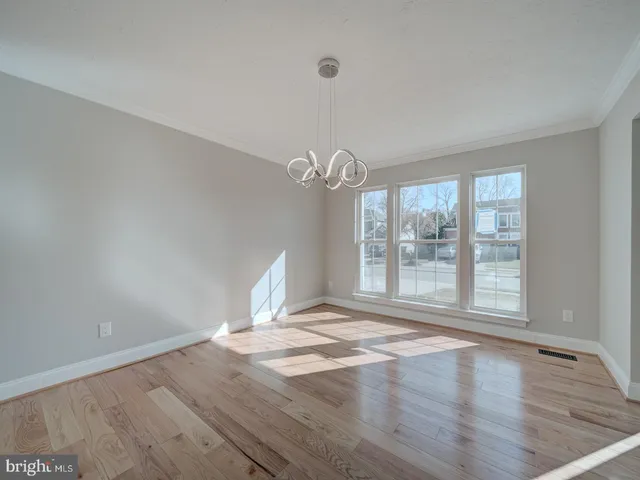 a view of an empty room with wooden floor and a cabinet