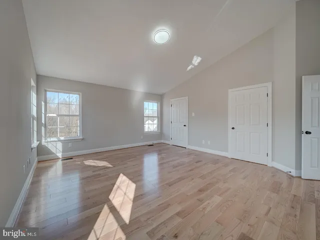 a large white kitchen with granite countertop a stove a sink a microwave and wooden floor