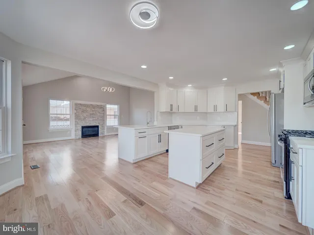 a view of empty room with wooden floor and kitchen