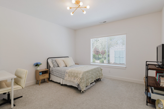 287 East 1000 North Logan, UT 84321 - Photo 22 of 41 Carpeted room featuring a large window with horizontal blinds, a modern light fixture, and a built-in shelving unit