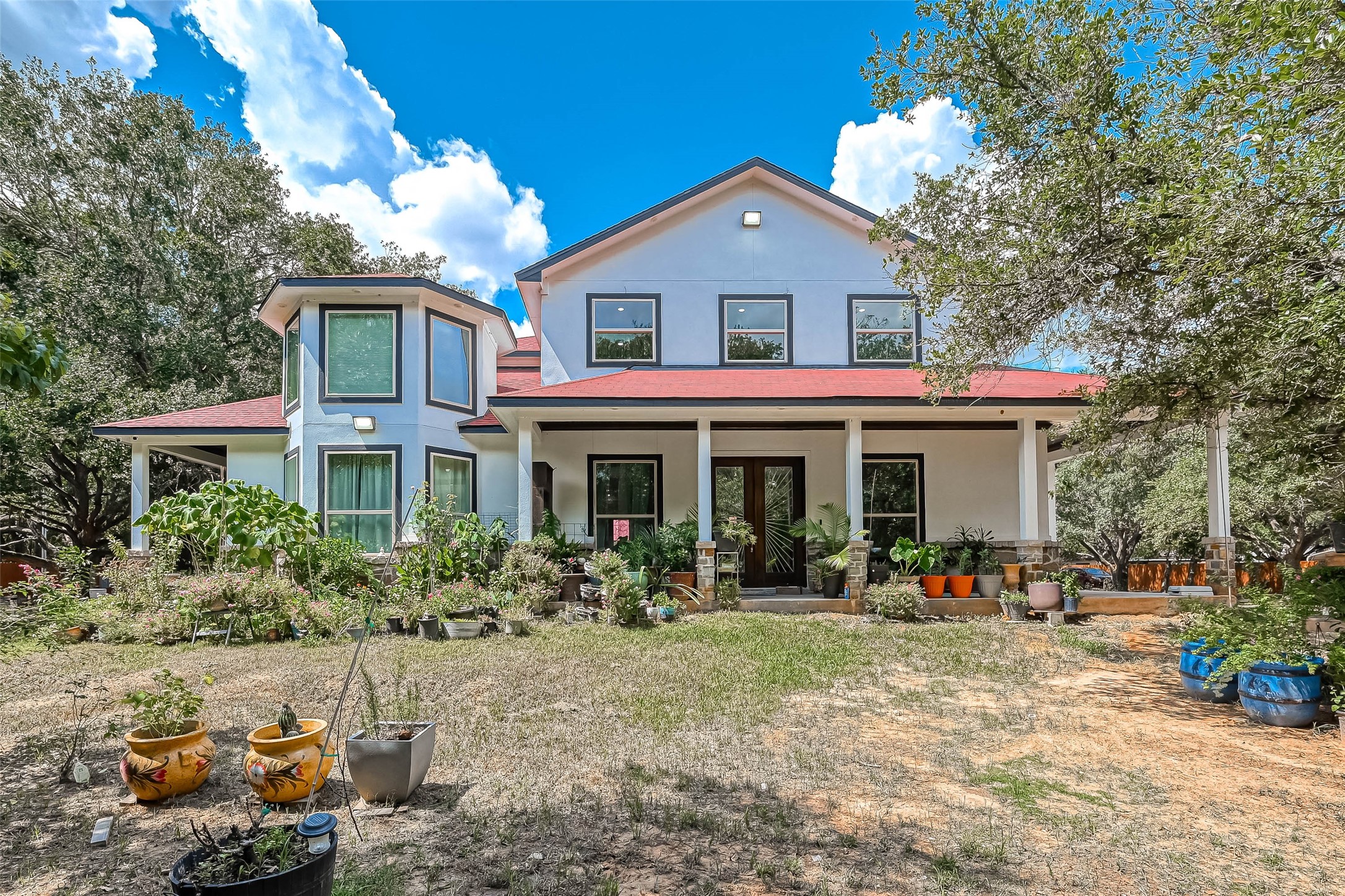 a front view of a house with lots of trees and plants