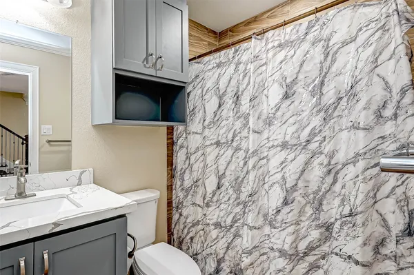 a bathroom with a granite countertop sink and a toilet