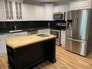 a kitchen with stainless steel appliances granite countertop a refrigerator a stove a sink and white cabinets