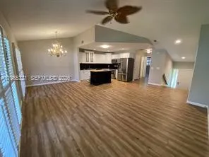 a view of a room with kitchen island stainless steel appliances wooden floor