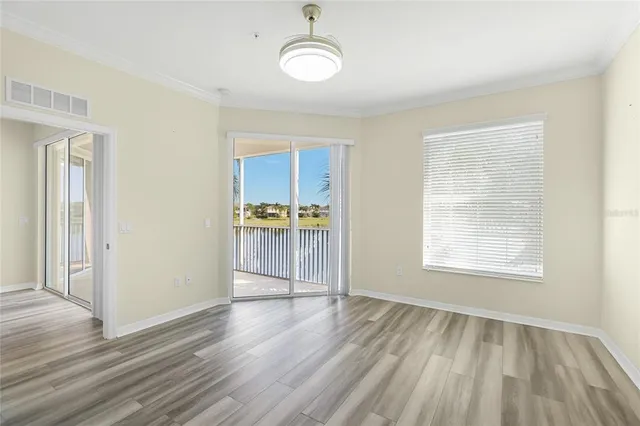 a view of empty room with wooden floor and fan