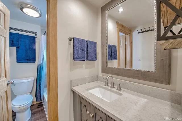 a bathroom with a granite countertop sink a toilet and a mirror