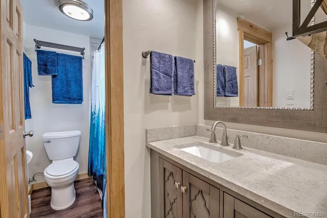a bathroom with a granite countertop toilet sink and mirror