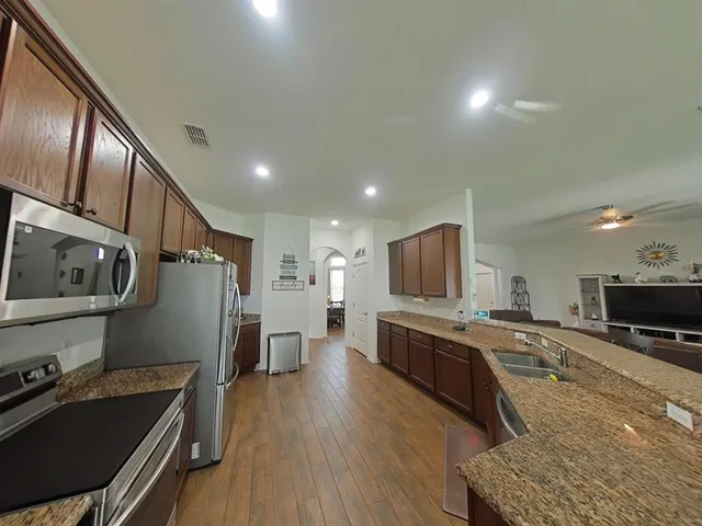 a kitchen with stainless steel appliances granite countertop a sink refrigerator and cabinets