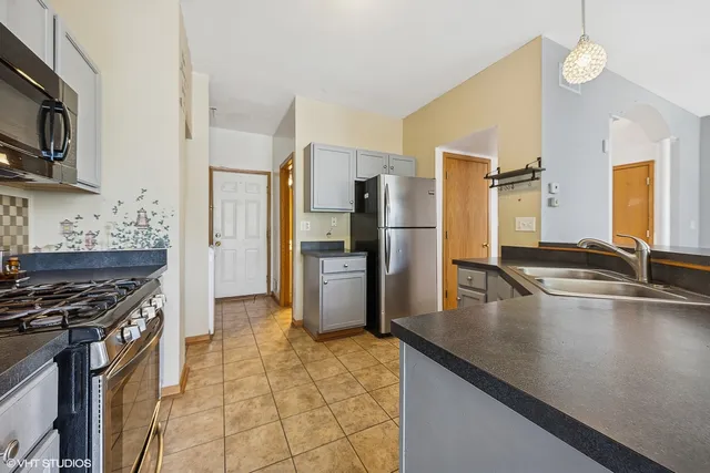 a kitchen with stainless steel appliances granite countertop a sink a stove and a refrigerator