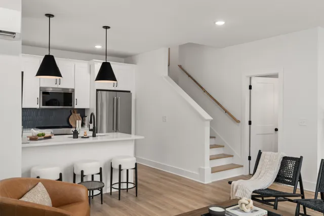 a kitchen with stainless steel appliances granite countertop a refrigerator a stove a sink dishwasher and white cabinets with wooden floor