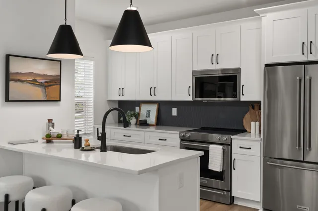 a kitchen with stainless steel appliances a refrigerator a sink a stove and white cabinets