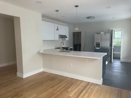 a room with kitchen island a sink and wooden floor