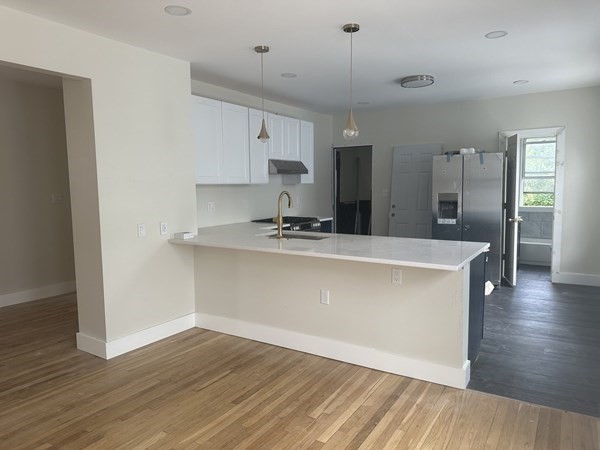 a room with kitchen island a sink and wooden floor