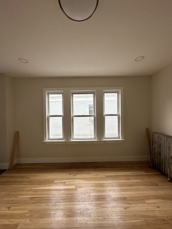 106 Rosseter Street, Unit 3 Boston, MA 02121 - Photo 6 of 9 an empty room with wooden floor and windows