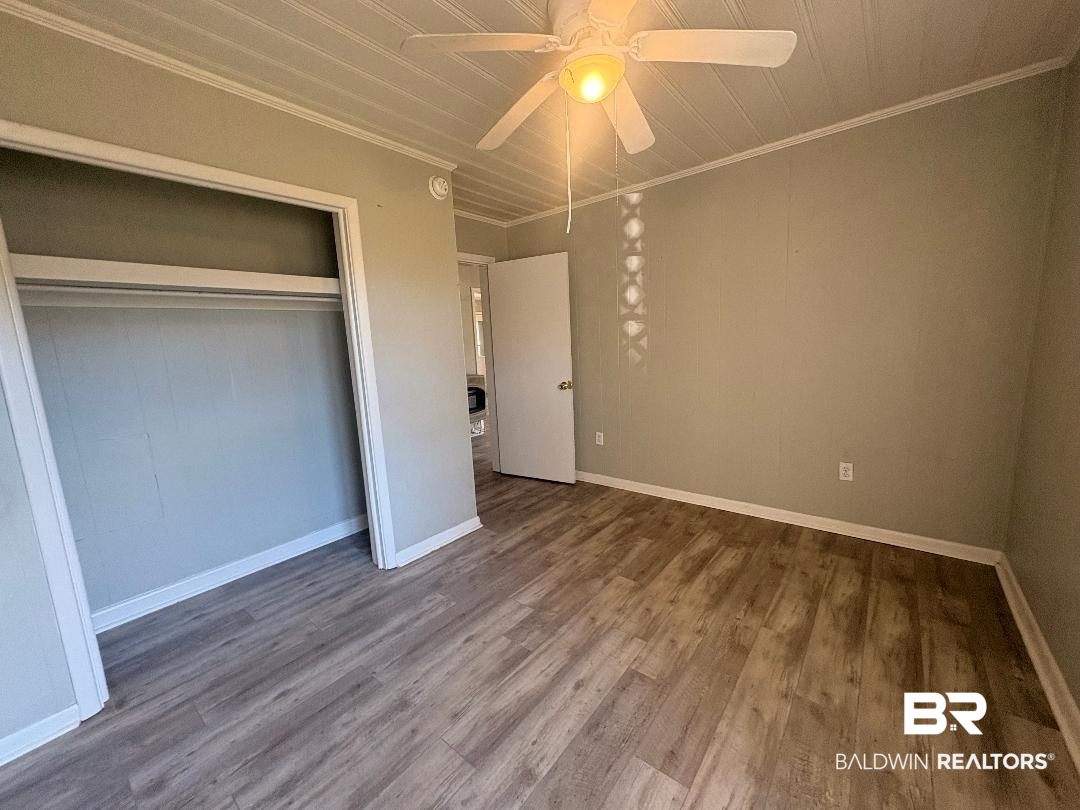 9330 Pinewood Avenue, Unit S 1 2 3 4 Elberta, AL 36530 - Photo 9 of 12 Unfurnished bedroom with ornamental molding, ceiling fan, wood finished floors, and a closet