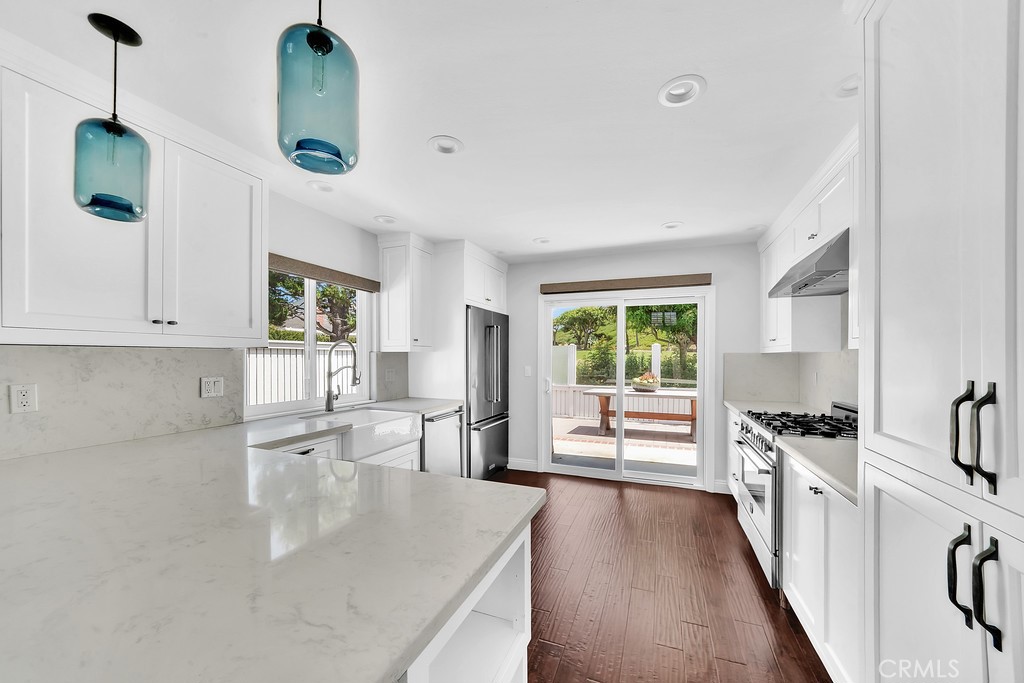 33902 Faeroe Bay Dana Point, CA 92629 - Photo 6 of 22 a kitchen with granite countertop a stove a sink a refrigerator and white cabinets with wooden floor