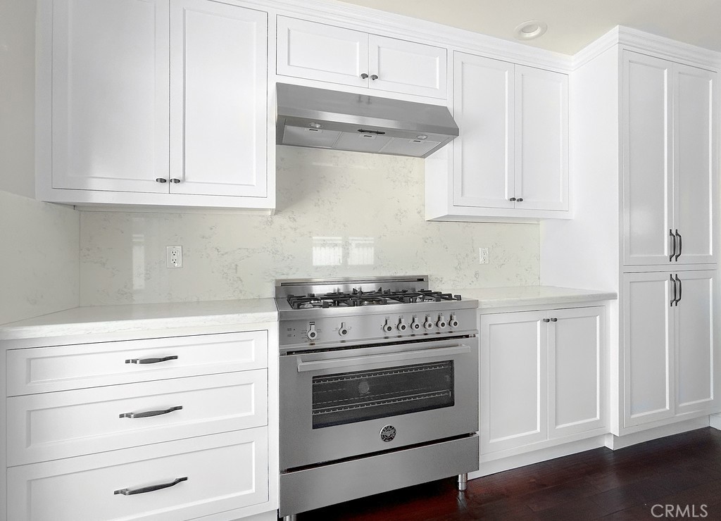 33902 Faeroe Bay Dana Point, CA 92629 - Photo 7 of 22 a kitchen with granite countertop white cabinets and a stove with wooden floor
