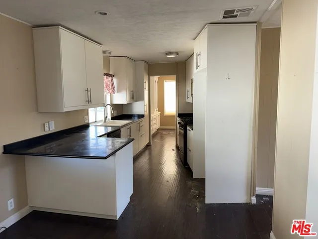 a kitchen with granite countertop a sink stove and cabinets