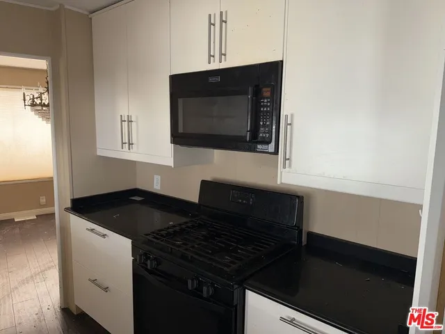 a kitchen with granite countertop white cabinets and black appliances