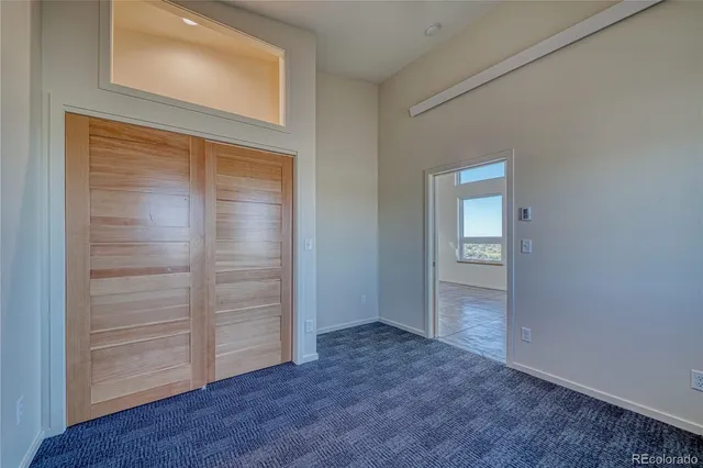 an empty room with wooden floor closet and windows