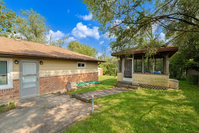 a view of a house with table and chairs next to a yard