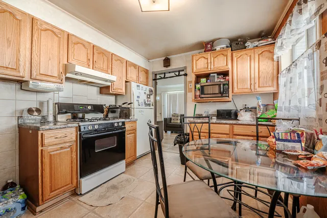 a kitchen with stainless steel appliances granite countertop a stove top oven a sink a dining table and chairs