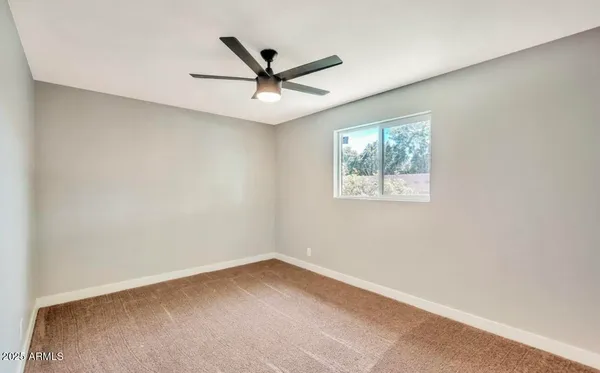 an empty room with a window and a fan