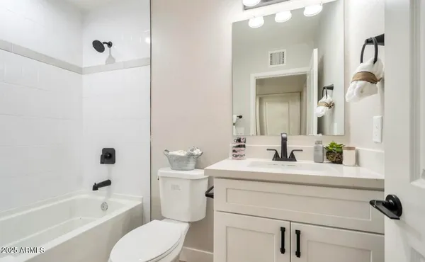 a bathroom with a toilet a sink a mirror a bathtub and vanity