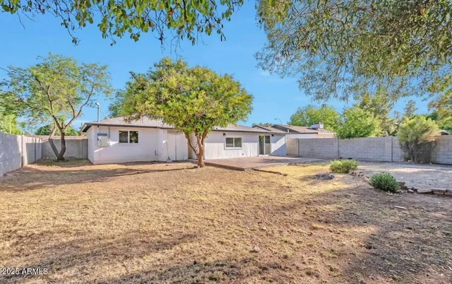a backyard of a house with large trees and wooden fence