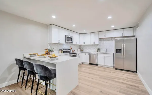 a kitchen with a sink a refrigerator and white cabinets